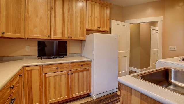 kitchen with white refrigerator, sink, and hardwood / wood-style floors