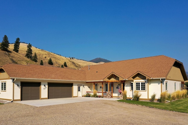 ranch-style home with a porch, a garage, and a mountain view