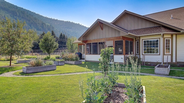 view of front facade featuring a mountain view, a sunroom, and a front lawn