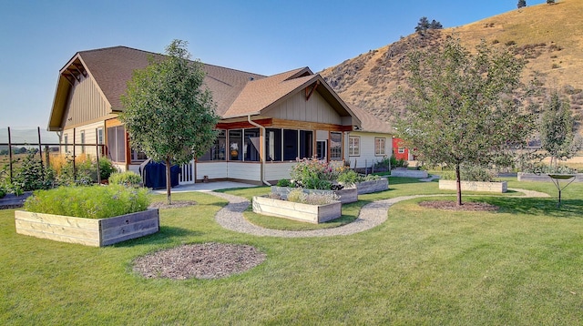 rear view of house featuring a mountain view, a yard, and a sunroom