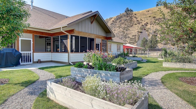 back of house featuring a mountain view, a lawn, and a sunroom