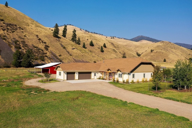 ranch-style home with a garage, a mountain view, and a front lawn