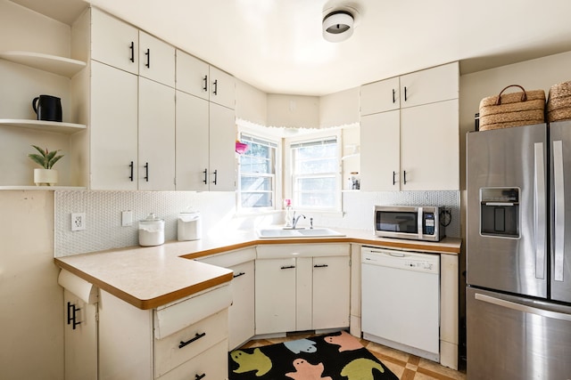 kitchen with stainless steel appliances, sink, backsplash, and white cabinetry