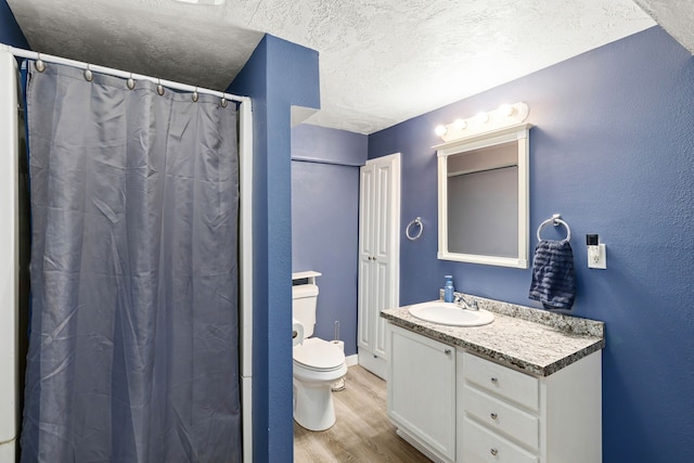 bathroom featuring a textured ceiling, vanity, hardwood / wood-style floors, walk in shower, and toilet