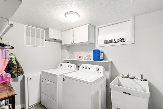 laundry room featuring a textured ceiling, sink, cabinets, and separate washer and dryer