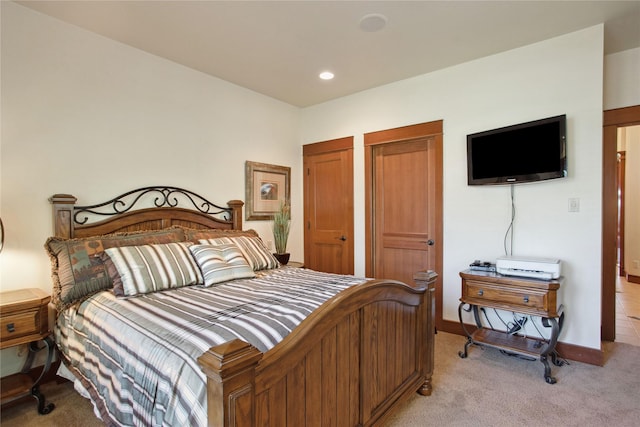 bedroom featuring recessed lighting, baseboards, two closets, and light carpet