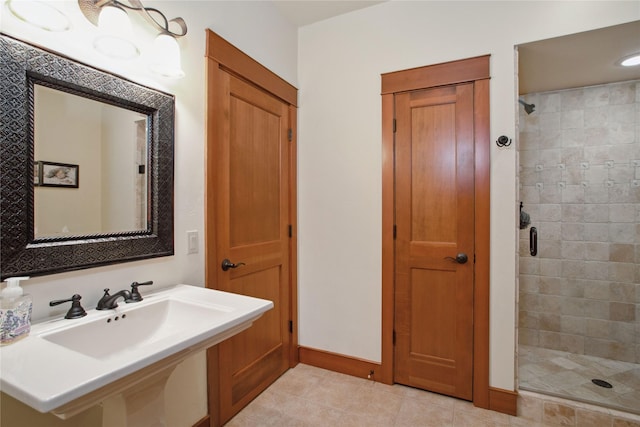 bathroom with a sink, baseboards, tile patterned flooring, and a stall shower