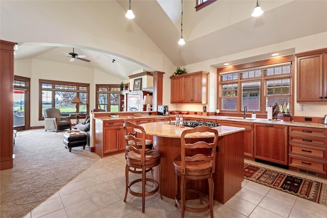 kitchen with ceiling fan, a sink, a peninsula, decorative columns, and stainless steel gas stovetop