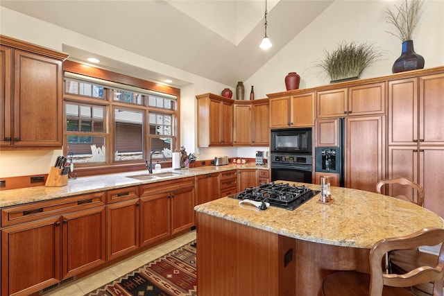 kitchen featuring light stone counters, a sink, a breakfast bar area, light tile patterned floors, and black appliances