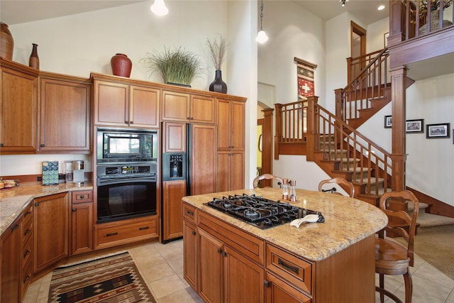 kitchen featuring a high ceiling, light stone countertops, light tile patterned floors, and black appliances