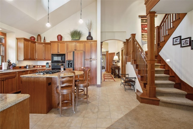 kitchen featuring high vaulted ceiling, a kitchen bar, arched walkways, light tile patterned floors, and black appliances