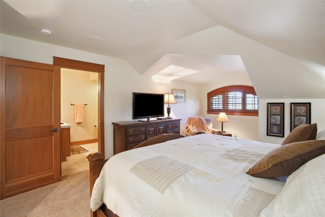 bedroom with light colored carpet, ensuite bath, and lofted ceiling