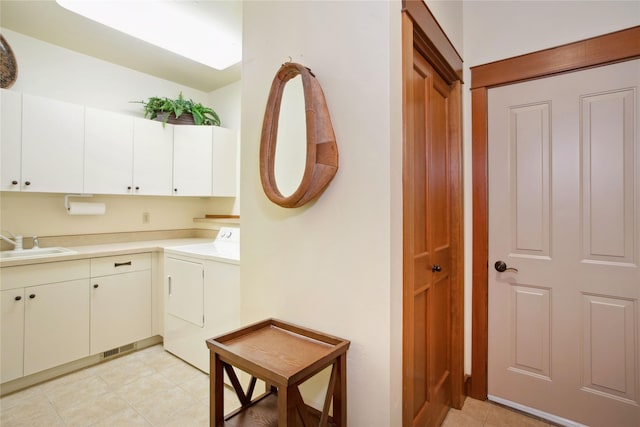 kitchen with light countertops, white cabinets, a sink, independent washer and dryer, and light tile patterned floors