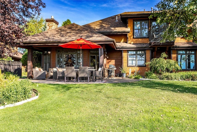 rear view of property featuring fence, a patio, a chimney, a shingled roof, and a yard