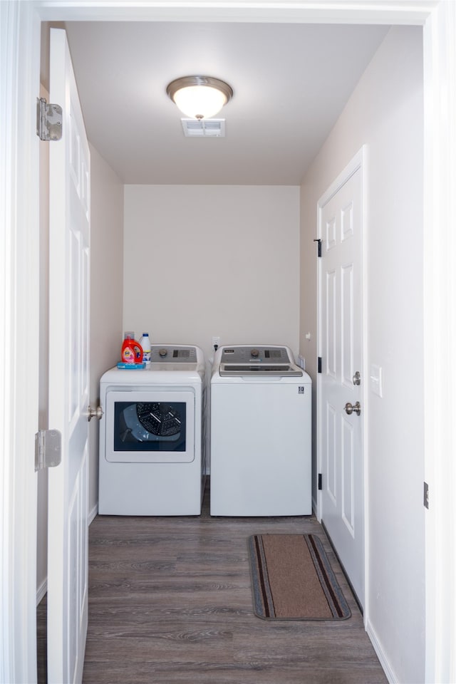 clothes washing area with dark hardwood / wood-style flooring and washer and dryer