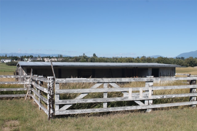 view of horse barn featuring a mountain view and a rural view