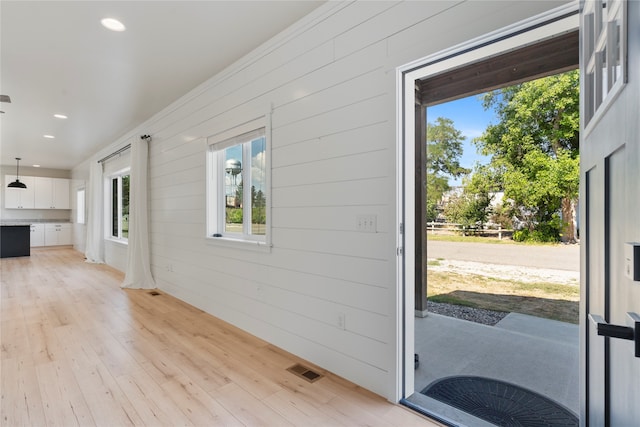 doorway to outside featuring wooden walls and light hardwood / wood-style floors