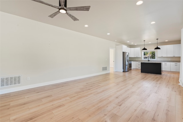 unfurnished living room featuring ceiling fan, sink, and light hardwood / wood-style floors