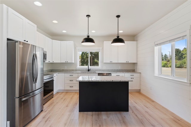 kitchen featuring hanging light fixtures, a center island, light hardwood / wood-style flooring, stainless steel appliances, and sink