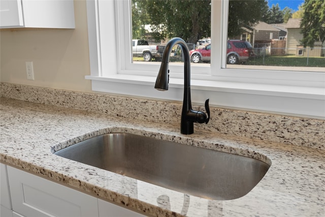 room details with light stone countertops, white cabinetry, and sink