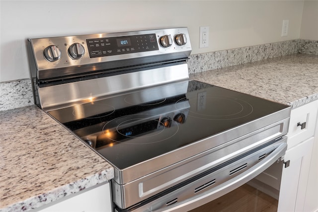 details featuring white cabinets, light stone counters, and electric stove