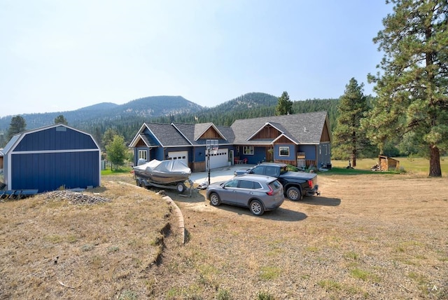 view of front of house featuring a shed, a front lawn, and a mountain view