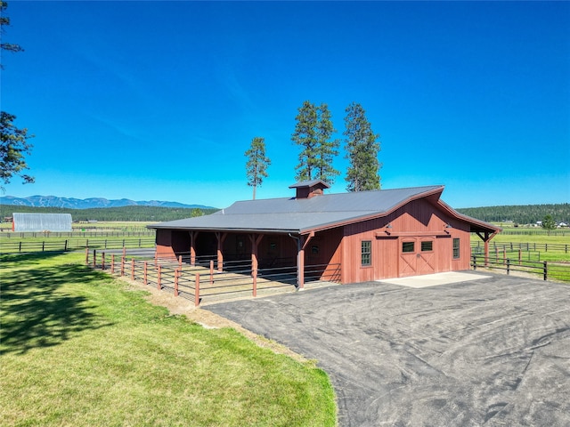 view of horse barn featuring a mountain view and a rural view