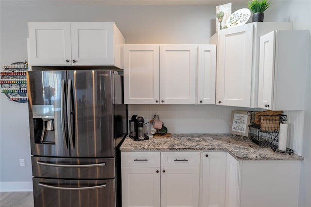 kitchen with stainless steel fridge with ice dispenser, light stone counters, white cabinets, and light hardwood / wood-style floors