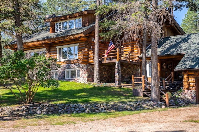 2100 Four Mile Way, Kalispell, MT 59901 - view of front facade featuring log exterior, stone siding, a front yard, and a deck