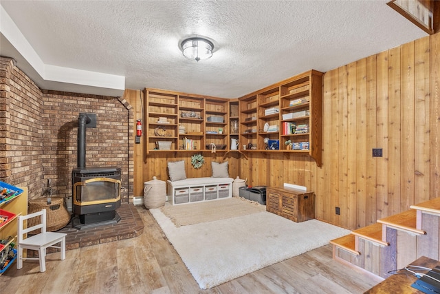 2100 Four Mile Way, Kalispell, MT 59901 - sitting room featuring wood finished floors, a wood stove, wood walls, a textured ceiling, and stairs