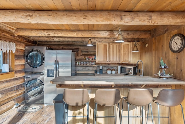 2100 Four Mile Way, Kalispell, MT 59901 - kitchen featuring estacked washer and dryer, rustic walls, a wooden ceiling with exposed beams, stainless steel appliances, and wood finished floors