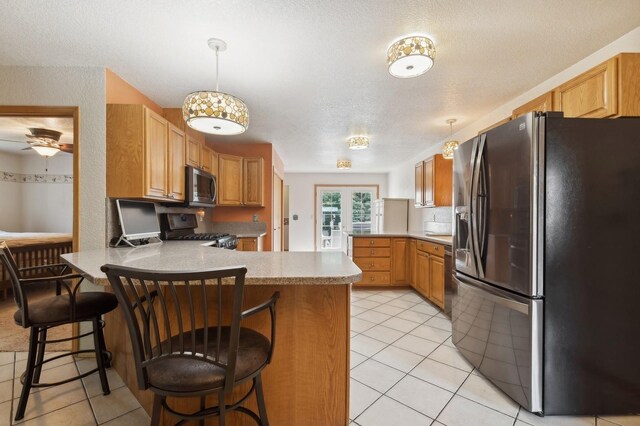 kitchen with range with gas cooktop, kitchen peninsula, a breakfast bar area, and fridge with ice dispenser