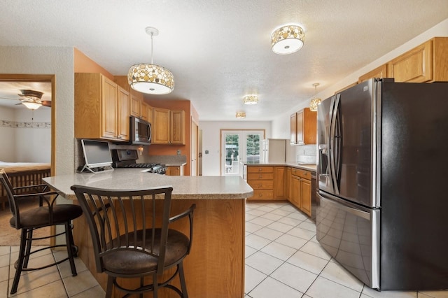 kitchen with a peninsula, light tile patterned floors, french doors, and appliances with stainless steel finishes