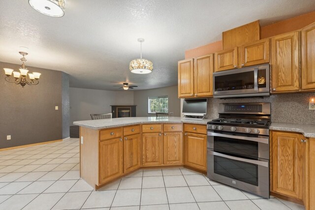 kitchen featuring backsplash, pendant lighting, kitchen peninsula, stainless steel appliances, and ceiling fan with notable chandelier