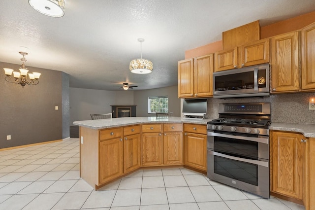 kitchen with backsplash, light countertops, appliances with stainless steel finishes, a peninsula, and light tile patterned flooring