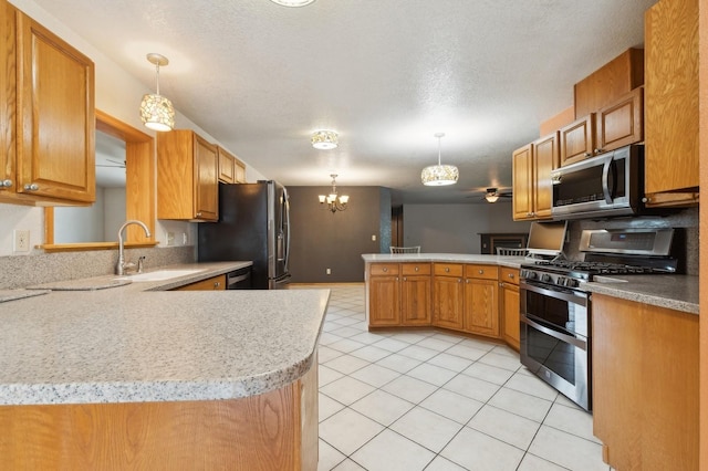 kitchen with a peninsula, a sink, hanging light fixtures, light countertops, and appliances with stainless steel finishes