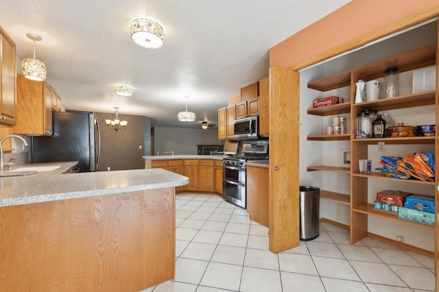 kitchen featuring a peninsula, light tile patterned flooring, a sink, stainless steel appliances, and decorative light fixtures