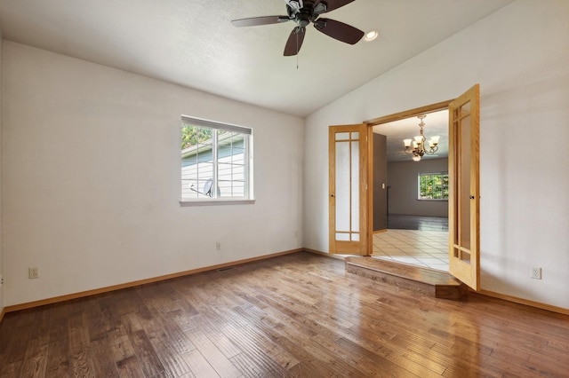 spare room with baseboards, lofted ceiling, wood-type flooring, and ceiling fan with notable chandelier