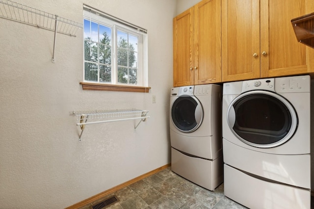 clothes washing area with washer and dryer and cabinets