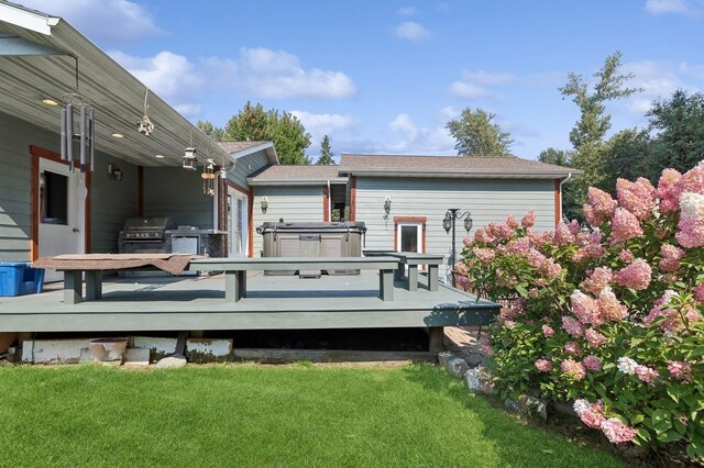 deck featuring a grill, a hot tub, and a lawn