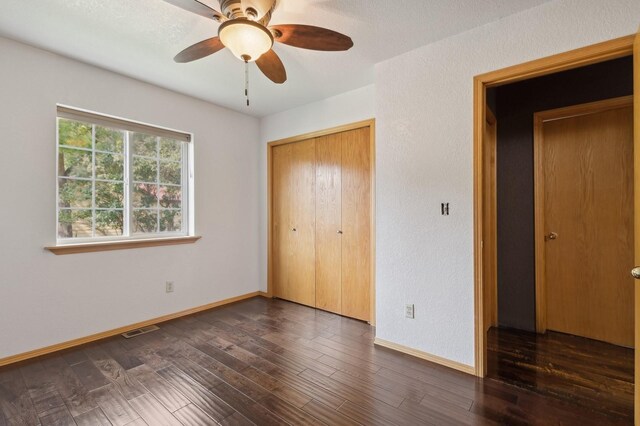 unfurnished bedroom featuring ceiling fan, dark hardwood / wood-style flooring, and a closet