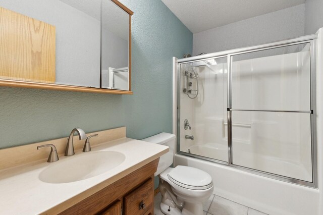 full bathroom featuring toilet, vanity, tile patterned floors, enclosed tub / shower combo, and a textured ceiling