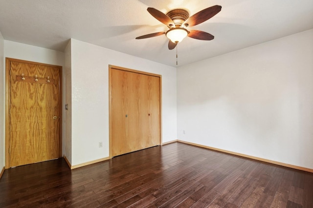 unfurnished bedroom with dark wood-style floors, ceiling fan, baseboards, and a closet