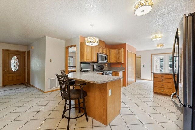 kitchen with light tile patterned floors, a kitchen bar, kitchen peninsula, stainless steel appliances, and hanging light fixtures