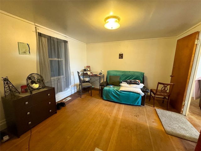 living area with crown molding and light hardwood / wood-style floors