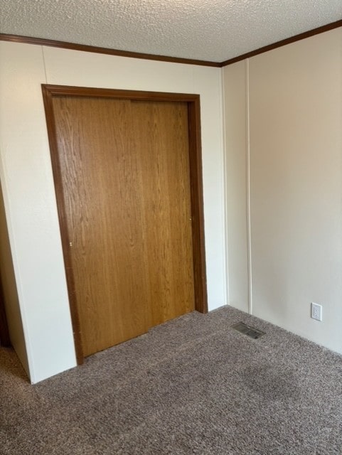 unfurnished bedroom with a closet, carpet flooring, a textured ceiling, and visible vents