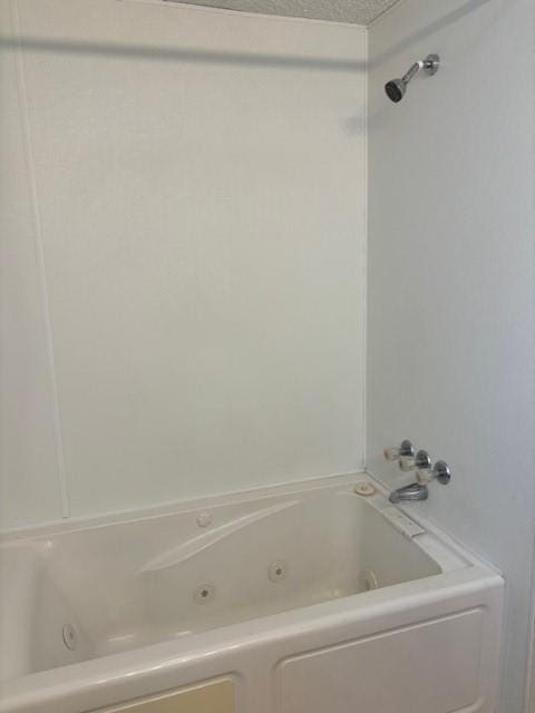 full bathroom with a textured ceiling and a combined bath / shower with jetted tub