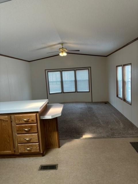 interior space featuring visible vents, lofted ceiling, ceiling fan, ornamental molding, and light colored carpet