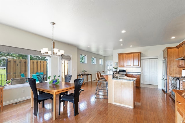 dining room with a notable chandelier, light hardwood / wood-style flooring, and sink