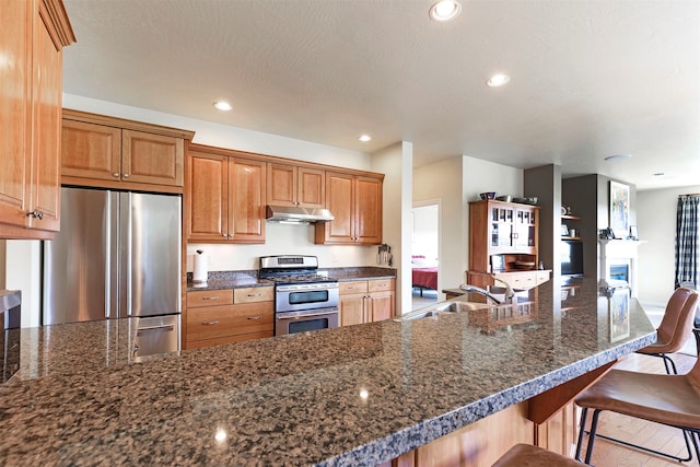 kitchen featuring a textured ceiling, appliances with stainless steel finishes, sink, and a breakfast bar area